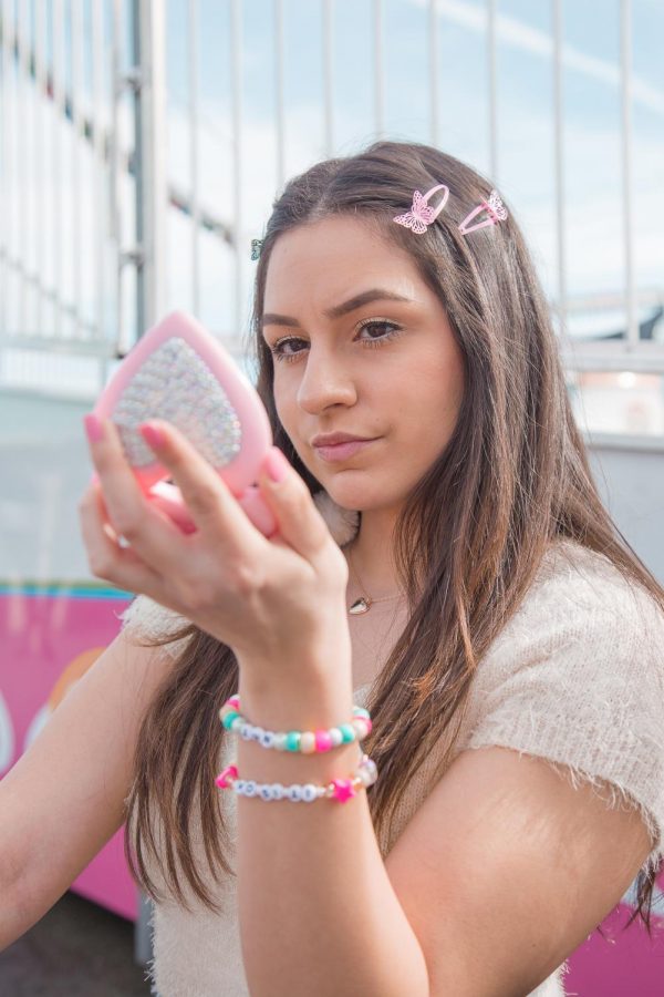 Model Natalie Cornejo shows off plastic beaded bracelets, pink hair-clips and a heart-shaped compact in this portrait shot.